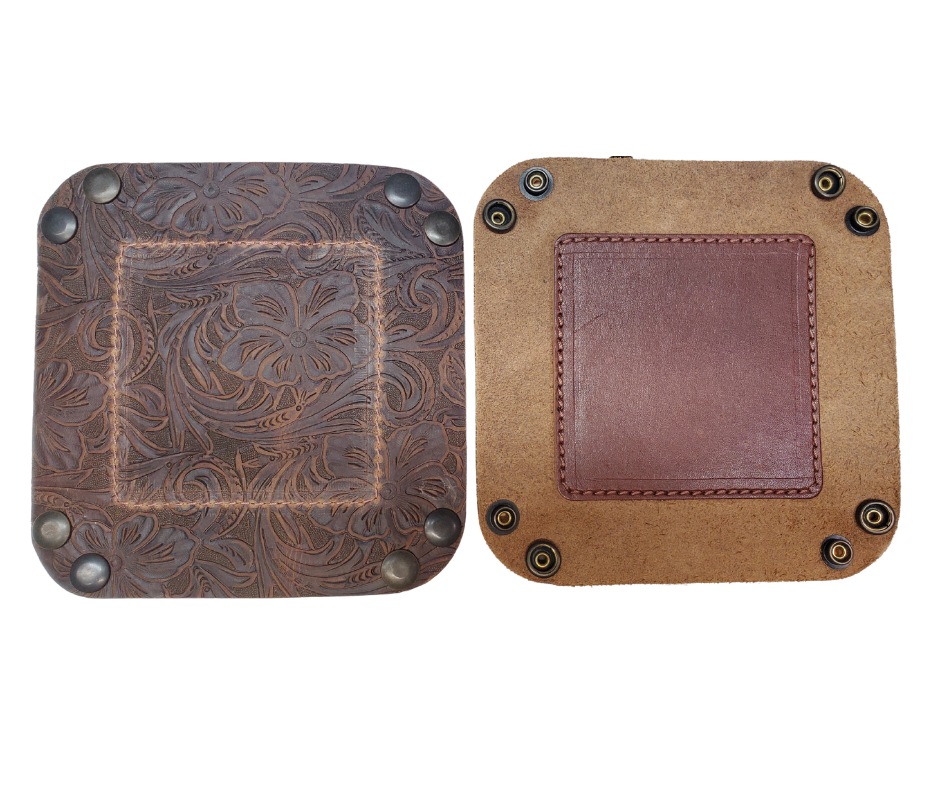 Our Western Leather Valet Tray, crafted in Smyrna, TN, easily folds flat by unsnapping its four Antique Brass snaps—perfect for travel. Its handy 4" x 4" size keeps your everyday essentials like keys and wallet organized. Featuring a classic embossed floral design, it pairs effortlessly with any style. Pick your favorite from four Black and Brown combos! Colors my vary.