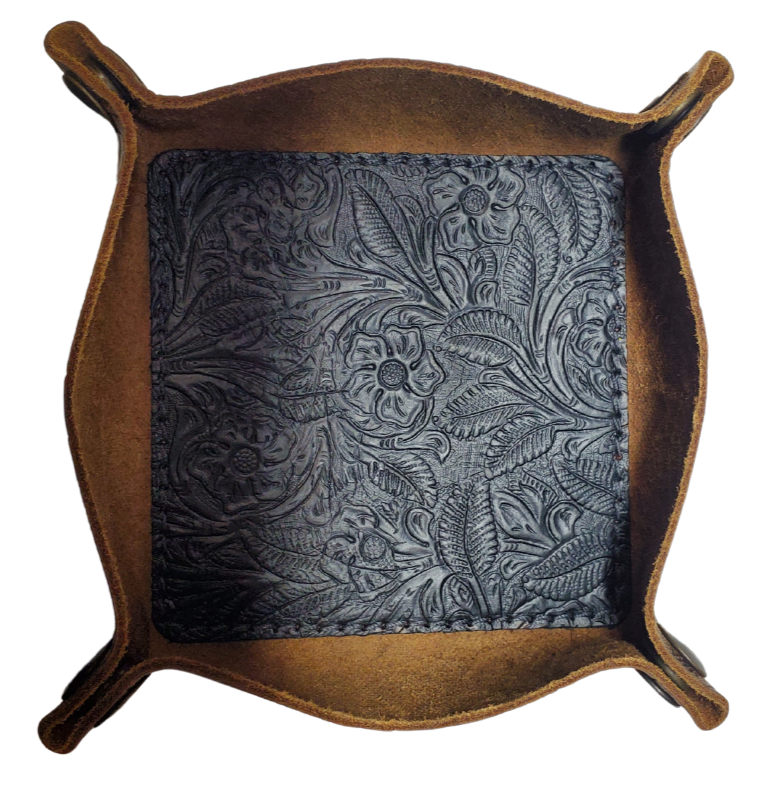 Our Western Leather Valet Tray, crafted in Smyrna, TN, easily folds flat by unsnapping its four Antique Brass snaps—perfect for travel. Its handy 4" x 4" size keeps your everyday essentials like keys and wallet organized. Featuring a classic embossed floral design, it pairs effortlessly with any style. Pick your favorite from four Black and Brown combos! Colors my vary.