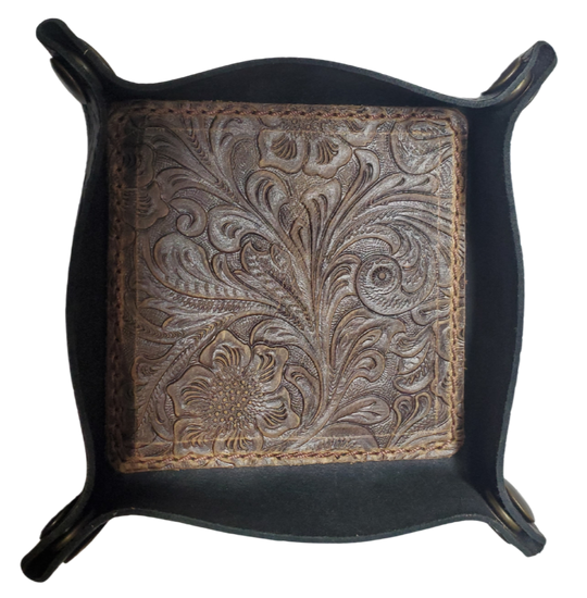Our Western Leather Valet Tray, crafted in Smyrna, TN, easily folds flat by unsnapping its four Antique Brass snaps—perfect for travel. Its handy 4" x 4" size keeps your everyday essentials like keys and wallet organized. Featuring a classic embossed floral design, it pairs effortlessly with any style. Pick your favorite from four Black and Brown combos! Colors my vary.
