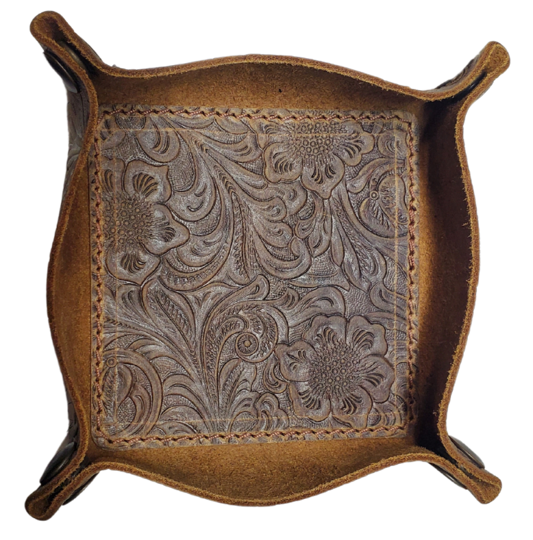 Our Western Leather Valet Tray, crafted in Smyrna, TN, easily folds flat by unsnapping its four Antique Brass snaps—perfect for travel. Its handy 4" x 4" size keeps your everyday essentials like keys and wallet organized. Featuring a classic embossed floral design, it pairs effortlessly with any style. Pick your favorite from four Black and Brown combos! Colors my vary.