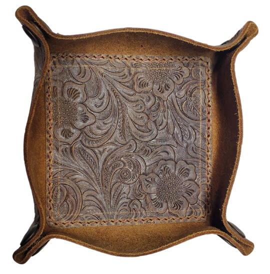 Our Western Leather Valet Tray, crafted in Smyrna, TN, easily folds flat by unsnapping its four Antique Brass snaps—perfect for travel. Its handy 4" x 4" size keeps your everyday essentials like keys and wallet organized. Featuring a classic embossed floral design, it pairs effortlessly with any style. Pick your favorite from four Black and Brown combos! Colors my vary.