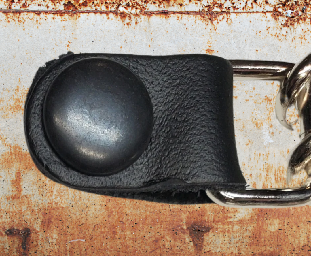 A close-up of a black leather vest chain snap.