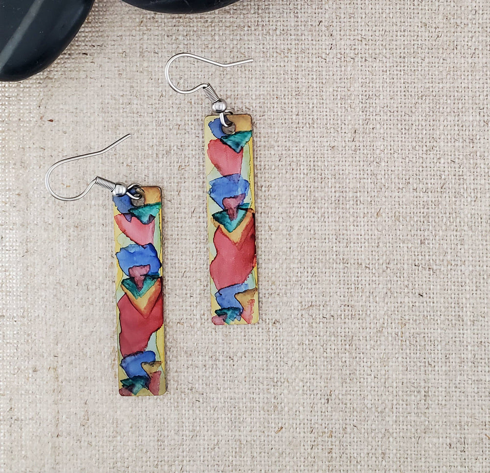 -The stainless steel earring blanks are hand painted with alcohol ink. -They are sealed to keep the finish. -The ear wires are stainless steel. -They measure 2 1/4" in length and 3/8" in width. -Medium weight -THE PHOTO IS AN EXAMPLE OF WHAT YOU WOULD RECEIVE. Each pair is one of a kind. Stocked at our Smyrna, TN shop down I-24 from downtown.