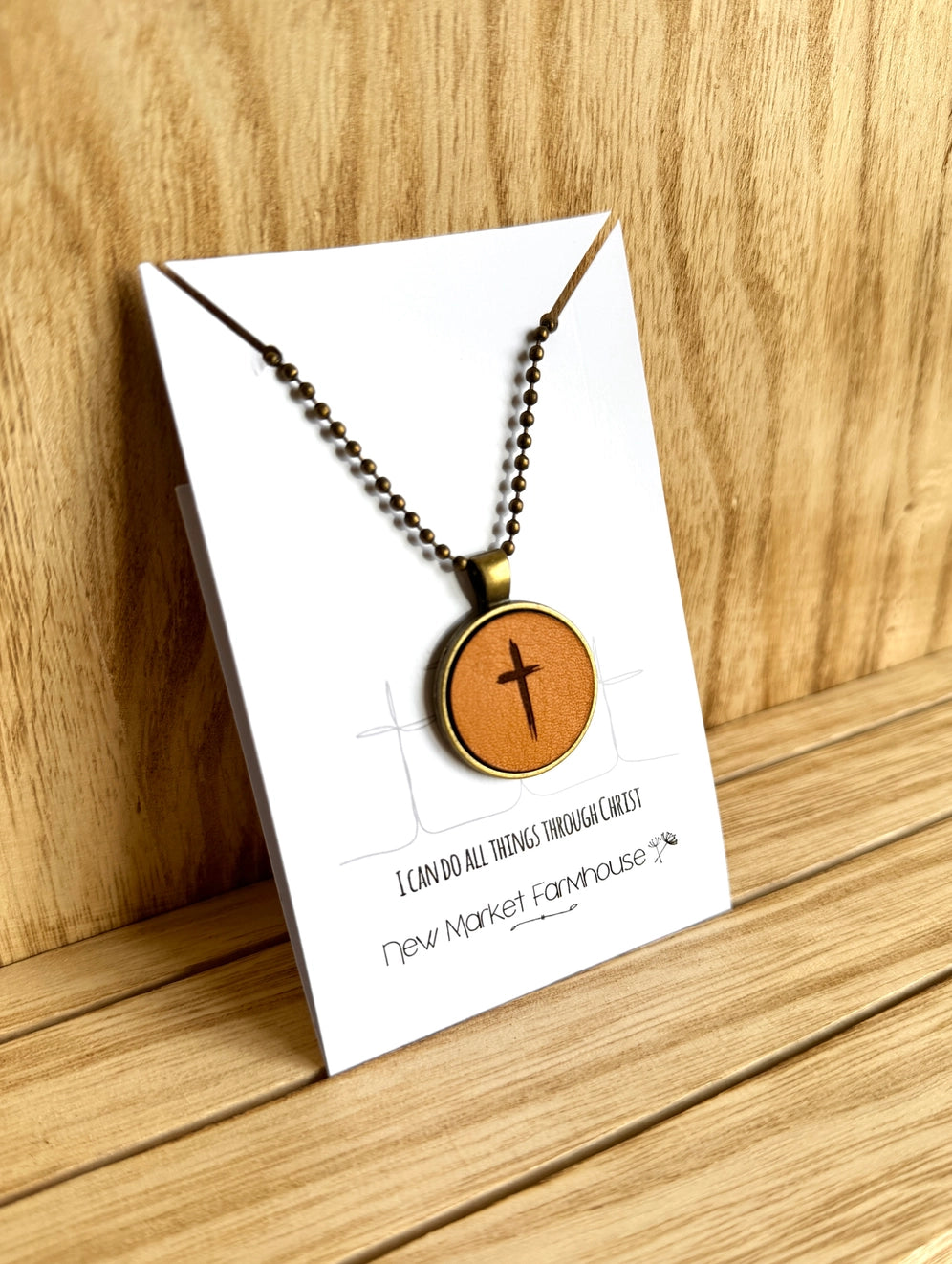 Farmhouse Leather Necklaces, Stocked at our Smyrna, TN shop. Currently offered in a Cross, Butterfly, and a Sunrise scene.

Each Necklace is made from laser engraved veg tan leather, set in an Antique Bronze 1" metal bezel and dangles from a matching 20" ball chain. Dimensions: 5 x 4 x 0.5 in.