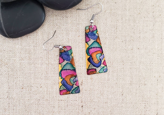 -The earrings are hand cut and finished copper blanks that are then hand painted with alcohol ink. -They are sealed to keep the finish. -The ear wires are stainless steel. -They measure 2" in length and 5/8" in width. -Light weight -THE PHOTO IS AN EXAMPLE OF WHAT YOU WOULD RECEIVE. Each pair is one of a kind. Stocked at our Smyrna, TN shop down I-24 from downtown.