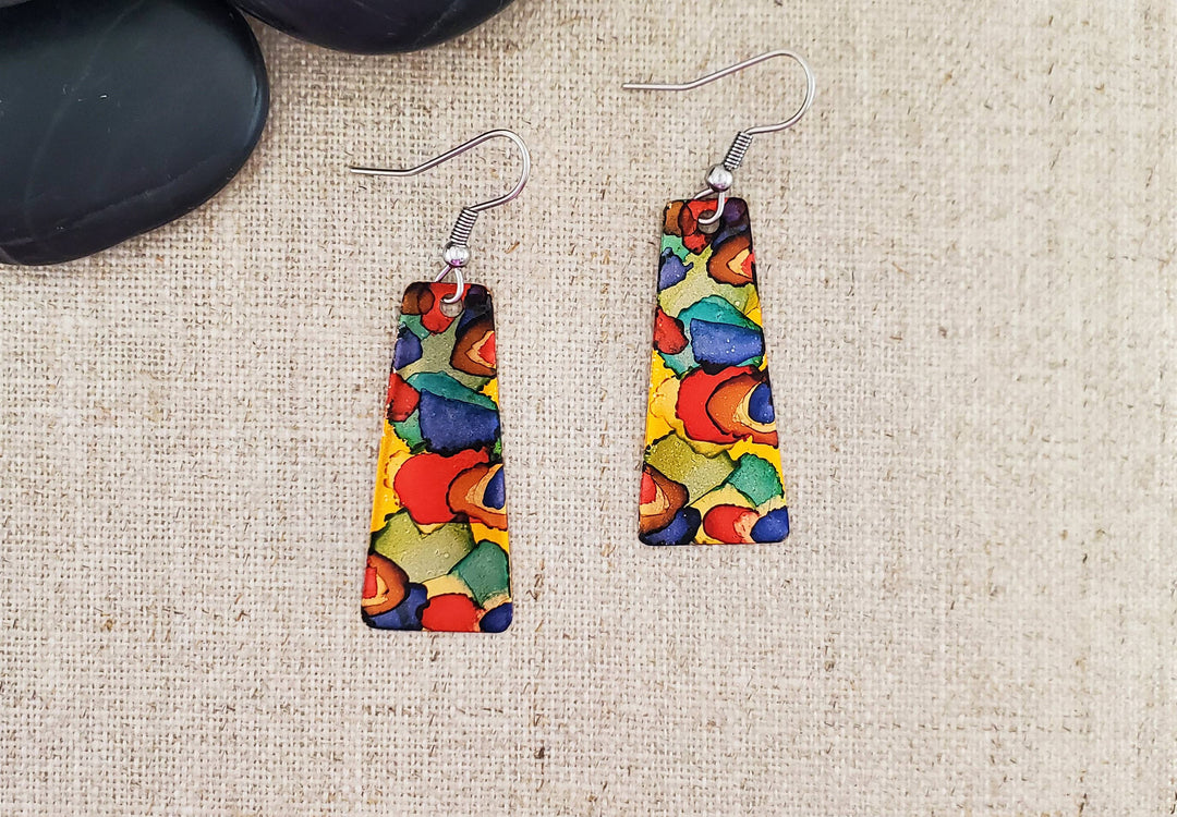 -The earrings are hand cut and finished copper blanks that are then hand painted with alcohol ink. -They are sealed to keep the finish. -The ear wires are stainless steel. -They measure 2" in length and 5/8" in width. -Light weight -THE PHOTO IS AN EXAMPLE OF WHAT YOU WOULD RECEIVE. Each pair is one of a kind. Stocked at our Smyrna, TN shop down I-24 from downtown.