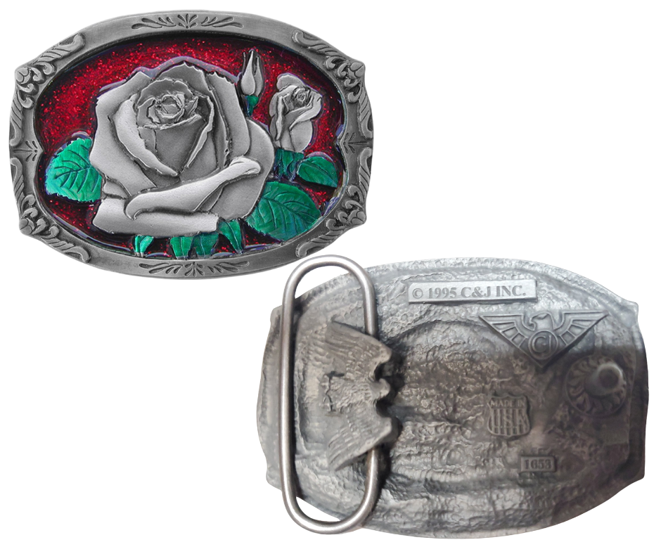 The "Rose Bud" belt buckle showcases a blooming rosebud highlighted with red and green enamel inlays, framed by a delicate filigree border on a semi-rectangular design. Proudly made in the USA, this solid metal cast buckle measures 2 7/8" by 2 1/16". Crafted from lead-free zinc aluminum and coated with non-toxic epoxy enamel, it fits belts up to 1 3/4" wide. Find this charming buckle in our Smyrna, TN shop just outside Nashville.