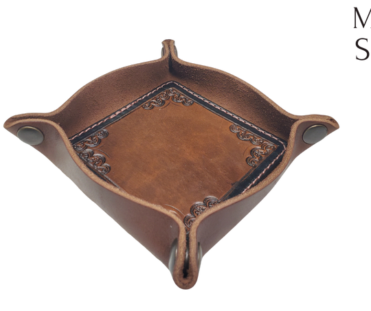 The Franklin is a little different than our other trays because of the Hand Stamped and stained inside layer. Outer layer is a Bison brown color with the inside layer being stitched in. The corners are held together with heavy line 24 Antique Brass colored snaps, for laying flat for travel, a place for placing keys, wallet, coins, etc. Made in our shop just outside Nashville in Smyrna, TN.