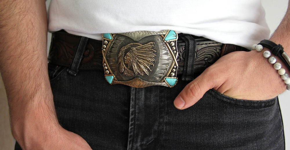 The Indian Chief buckle has a rectangle shape southwest design a centered by a feathered head dressed Chief framed by synthetic stones on each corner. This buckle is made from German Silver (nickel and brass alloy) or iron metal base. Some buckles have motifs made of copper, iron or brass and some are adorned with synthetic stones. Buckle size is Width Width 4” Height 3” and is available in our Smyrna, TN shop.