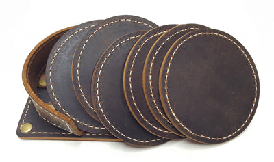 Handmade leather drink coasters with holder.  Made just outside Nashville in Smyrna, TN. Coasters come in set of 6 round 3 1/2" diameter pieces either with matching stitching or contrast stitching around the edges.  They are available in distressed brown. Color variations may occur within sets depending on hides available. Corral square piece of leather with rounded edges and rounded retaining edge approx. 1' tall riveted in place to provide secure placement of coasters when not in use.