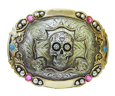 The Calavera buckle features a Sugar Skull accented by detailed Western scroll work and ornate border work with Pink and Blue stones.  Augus buckles are made from German Silver (nickel and brass alloy) or iron metal base. Some buckles have motifs made of copper, iron or brass. Each piece is punched, cut, soldered, engraved, polished and painted by our talented metal workers. Available at our Smyrna, TN location.