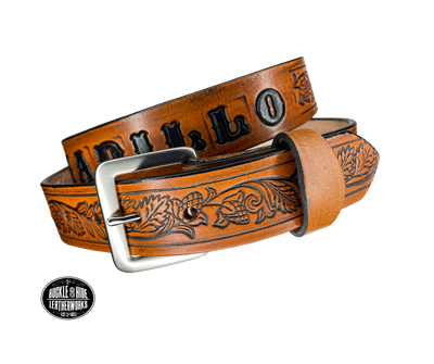 This solid strip of Veg Tan cowhide, is hand stained in 3 brown options, with smooth, finished edges. Embossed with Western Vine down length of belt, or have name added to scene up to 8 letters. Belt thickness is approx. 1/8", and 1 1/2" wide. Sizes available are 34" to 44" from buckle end to hole most worn. Attached with 2 snaps is a Brushed Nickel plated solid brass buckle. 