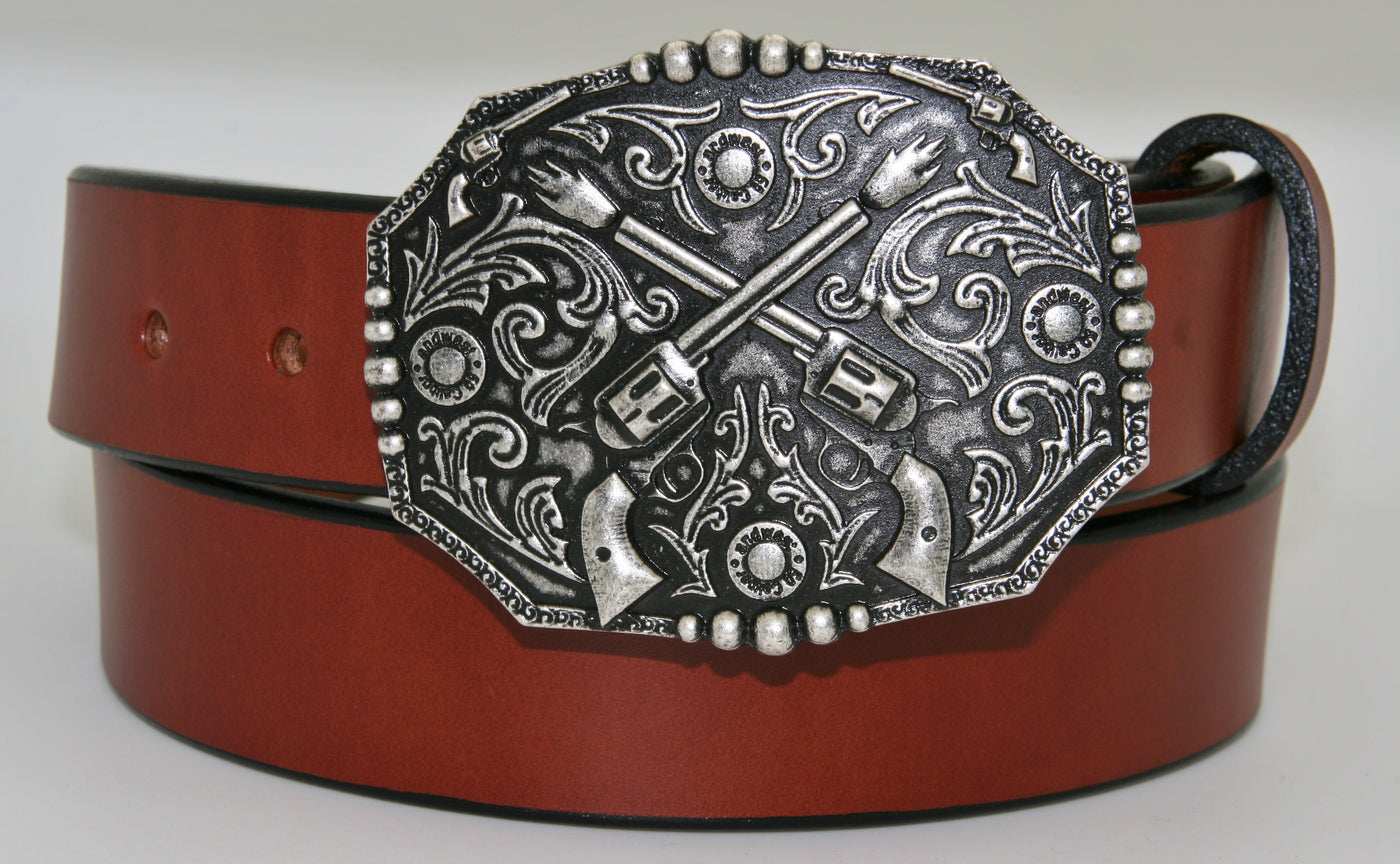 Crossed pistols buckle pictured on brown belt-This antique silver colored buckle by AndWest features a pair of crossed pistols centered on the oval shaped buckle with flattened sides. It also features 50 caliber shell end replicas within the Western scroll background design.  Fits belts up to 1 1/2" wide, dimensions are 3" tall by 4" wide.  Available in our online store as well as the retail shop in Smyrna, TN, just outside of Nashville.  This buckle is made in Mexico.