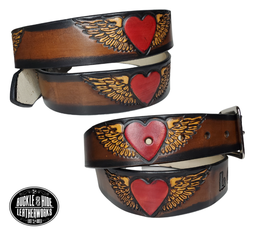 "The Love" is a handmade real leather belt made from a single strip of cowhide shoulder leather that is 8-10 oz. or approx. 1/8" thick. It has hand burnished (smoothed) edges and a Winged Heart pattern. This belt is completely HAND dyed with a multi step finishing technic or you can get in basic earth tones. The antique nickel plated solid brass buckle is snapped in place with heavy snaps.  This belt is made just outside Nashville in Smyrna, TN.