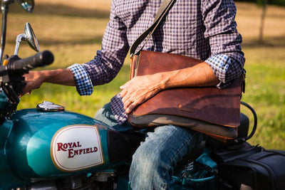 This leather messenger bag is made from soft real cowhide leather.  Flap is distressed brown leather and body has contrasting darker brown or black colored leather. The flap secures with a magnetic snap. Dimensions are approx. 15" by 12" by 3". Back pocket will hold a full size laptop.  Inner bag is lined with nylon and leather trim and hardware is brushed nickel. Available for purchase in our retail shop in Smyrna, TN, just outside Nashville.