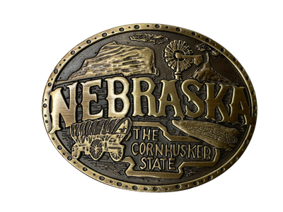 Nebraska State buckle by AndWest Dimensions are 3" tall by 3 3/4" wide Fits belts up to 1 1/2" wide Buckle is brass colored with Nebraska Cornhusker State embossed across front of buckle. Farming scene in the back behind "Nebraska". Back of buckle has Western scroll design Available in our online store and in the retail shop in Smyrna, TN, just outside of Nashville. Made in Mexico