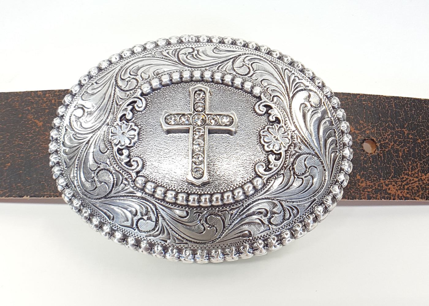 Antiqued finish with intricately detailed scroll background Center cross is accented with rhinestones A perfect way to dress up your wardrobe Dimensions: 3" tall by 3 3/4" wide Available online and in our shop just outside Nashville in Smyrna, TN.