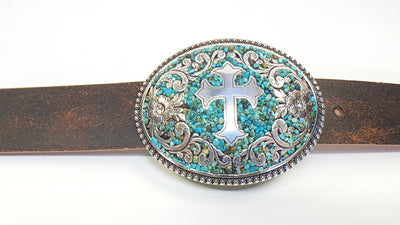 This Nocona buckle has a silver colored base with a raised Cross and Floral Filigree design. The design is revealed through a textured bed of glazed tiny pebbles, in turquoise color with earth tone highlights. The center of the flowers, on each end, displays a clear crystal. A beautiful buckle, from Blazin Roxx, that stands out with class. Fitting a belt of 1 1/2" wide, it's comfortable oval shape is 3 1/8" tall by 4" wide. Available for purchase online or in our shop in Smyrna, TN, just outside Nashville.