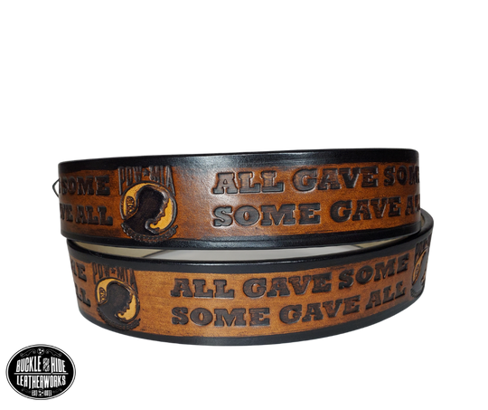 "The Veteran" is a handmade real leather belt made from a single strip of cowhide shoulder leather that is 8-10 oz. or approx. 1/8" thick. It has hand burnished (smoothed) edges and features a POW-MIA emblem along with "SOME GAVE ALL- ALL GAVE SOME pattern down the center. This belt is completely HAND dyed with a multi step finishing technic. The antique nickel plated solid brass buckle is snapped in place with heavy snaps.  This belt is made just outside Nashville in Smyrna, TN.