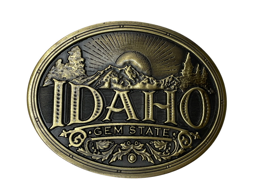 Idaho State buckle by AndWest Dimensions are 3" tall by 3 3/4" wide Fits belts up to 1 1/2" wide Buckle is brass colored with Idaho Gem State embossed across front of buckle. Mountain scene in the back behind "Idaho". Back of buckle has Western scroll design Available in our online store and in the retail shop in Smyrna, TN, just outside of Nashville. Made in Mexico
