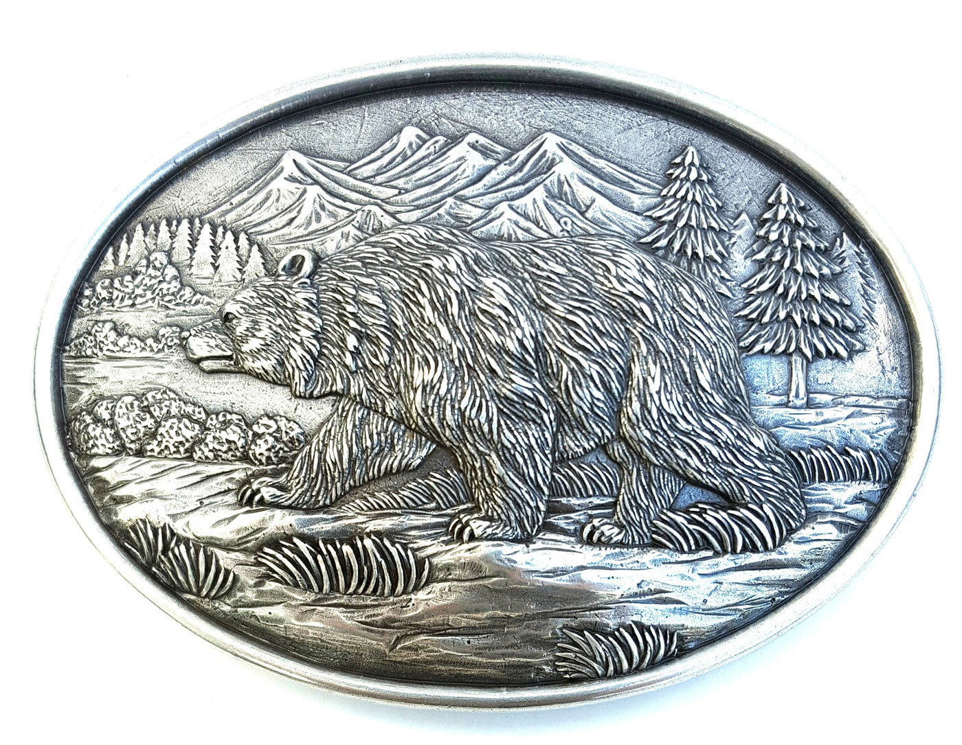 Nocona grizzly bear buckle, Nocona Western buckle Oval shaped buckle with a smooth edge accented with a bear walking in a mountain scenery. Measures: 3" X 4" Available online and in our shop in Smyrna, TN, just outside of Nashville.Nocona Western buckle Oval shaped buckle with a smooth edge accented with a bear walking in a mountain scenery. Measures: 3" X 4" Available online and in our shop in Smyrna, TN, just outside of Nashville.