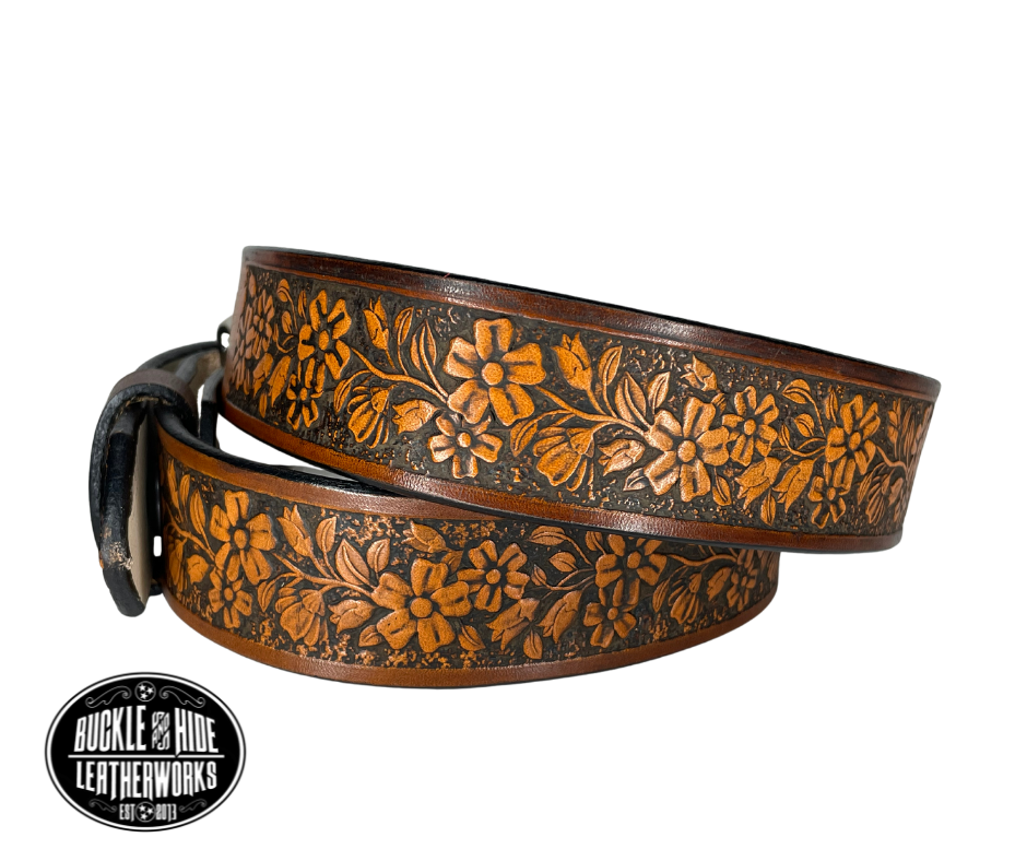 "The Beulah Land" is a handmade real leather belt made from a single strip of cowhide shoulder leather that is 8-10 oz. or approx. 1/8" thick. It has hand burnished (smoothed) edges and summer flowers embossed in 3 color options.  The antique nickel plated solid brass buckle is snapped in place with heavy snaps.  This belt is made just outside Nashville in Smyrna, TN.