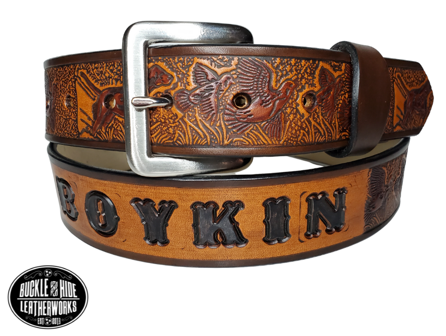 "The Retriever" is a handmade real leather belt made from a single strip of cowhide shoulder leather that is 8-10 oz. or approx. 1/8" thick. It has hand burnished (smoothed) edges and a Bird Hunting scene with a Bird Dog and Quail/Grouse pattern. This belt is completely HAND dyed with a multi step finishing technic. The antique nickel plated solid brass buckle is snapped in place with heavy snaps.  This belt is made just outside Nashville in Smyrna, TN.