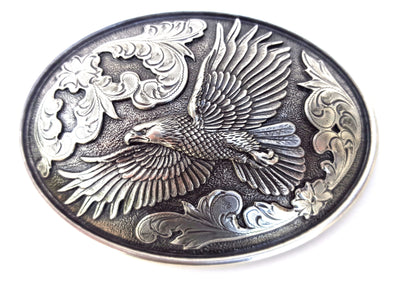 Nocona Eagle buckle, Nocona Western buckle  Smooth edge oval shaped buckle centered with a flying eagle and floral scroll on either side of it. Measures: 3" tall X 4" wide Available online and in our shop in Smyrna, TN, just outside of Nashville
