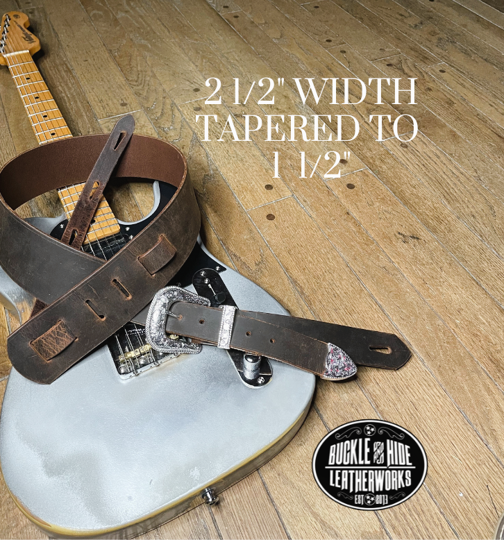 You don't get more classic than a handcrafted Distressed leather guitar strap! Featuring a ornate 3 piece western buckle set in the front position of the strap. Each size of buckle set is similar but not the same, so check out pictures. It's made from 1/8" thick drum distressed water buffalo and looks like a vintage "Tele". The main strap is made from a single strip of leather with beveled and .  Choose a 2" or 2 1/2" wide strap with a classic adjustment style.  Made just outside Nashville in Smyrna, TN.
