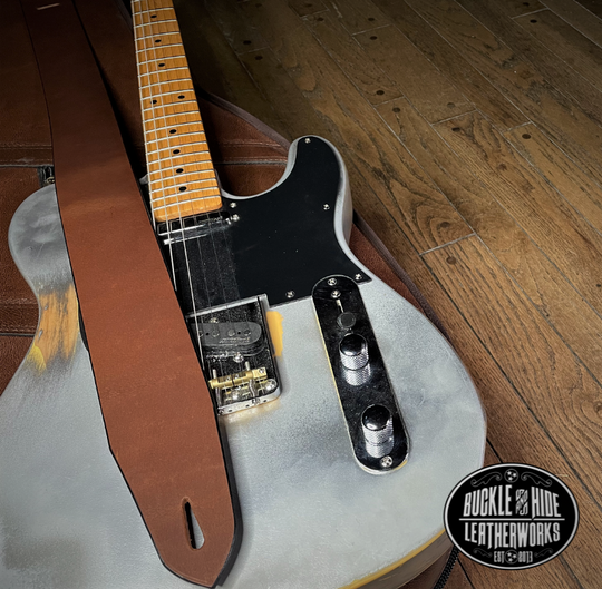 This is our basic "Tone" series. Not Flashy but all Tone! It's made from 1/8" thick drum Peanut Brown or Denim water Buffalo leather and looks great with a vintage Tele, Strat or Acoustic guitars. The main strap is made from a single strip of leather with beveled and .  Made just outside Nashville in Smyrna, TN. Choose a 2" or 2 1/2" wide strap with a classic adjustment style.   